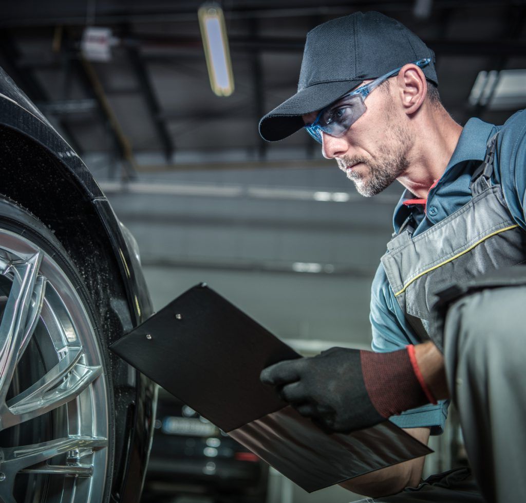 Mechanic with a clipboard inspecting a tyre - Car Garage in Raunds - Servicing, Brakes, Tyres & Diagnostics